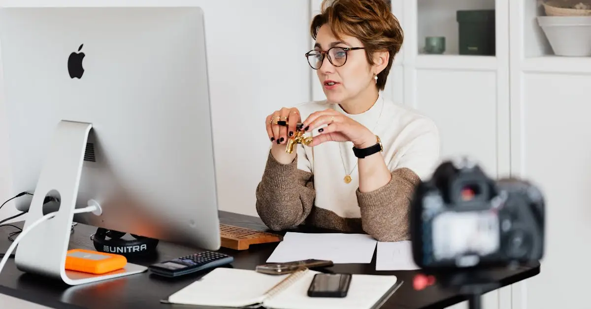 A professional woman engaged in a virtual meeting setup at her home desk, using a computer and camera.